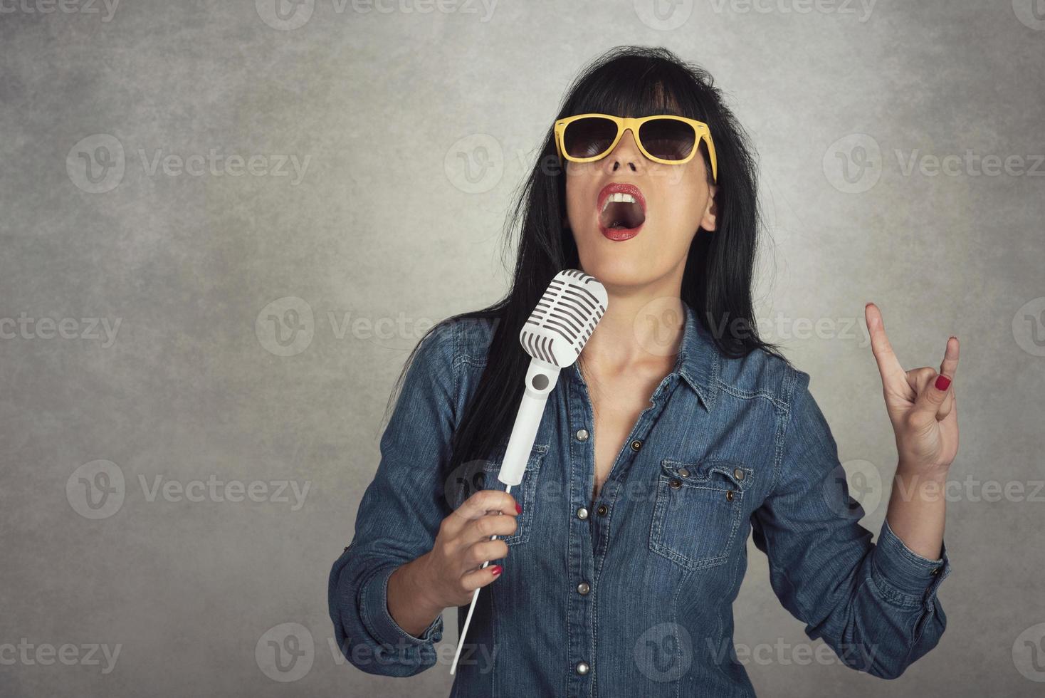 junge frau, die ein singendes mikrofon hält foto