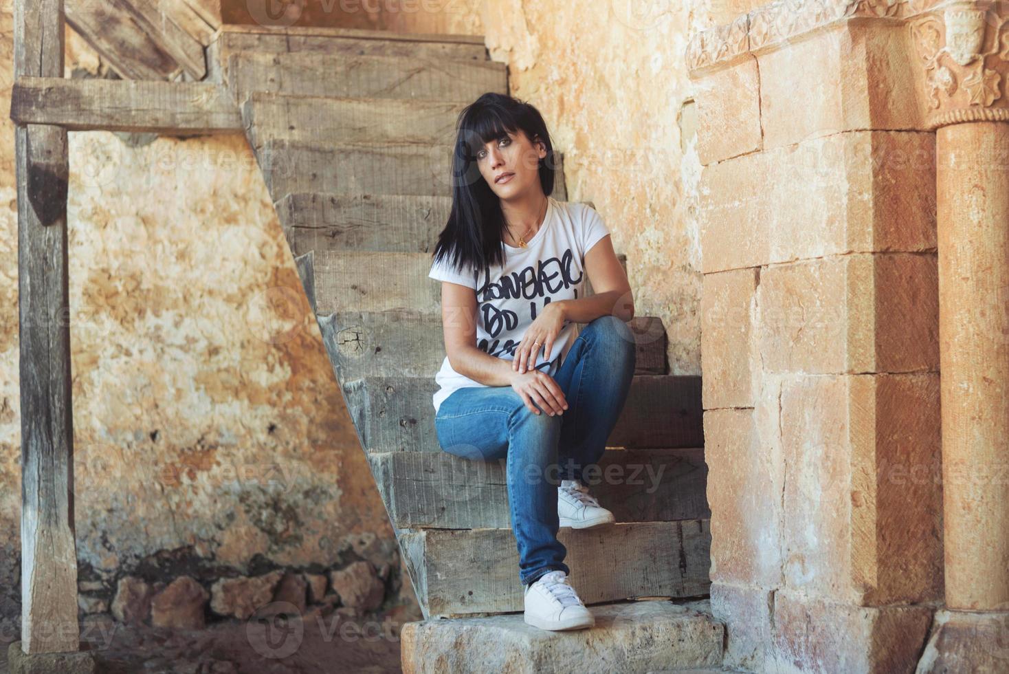 Mädchen sitzt auf der Treppe in der Nähe der alten grungigen Wand foto