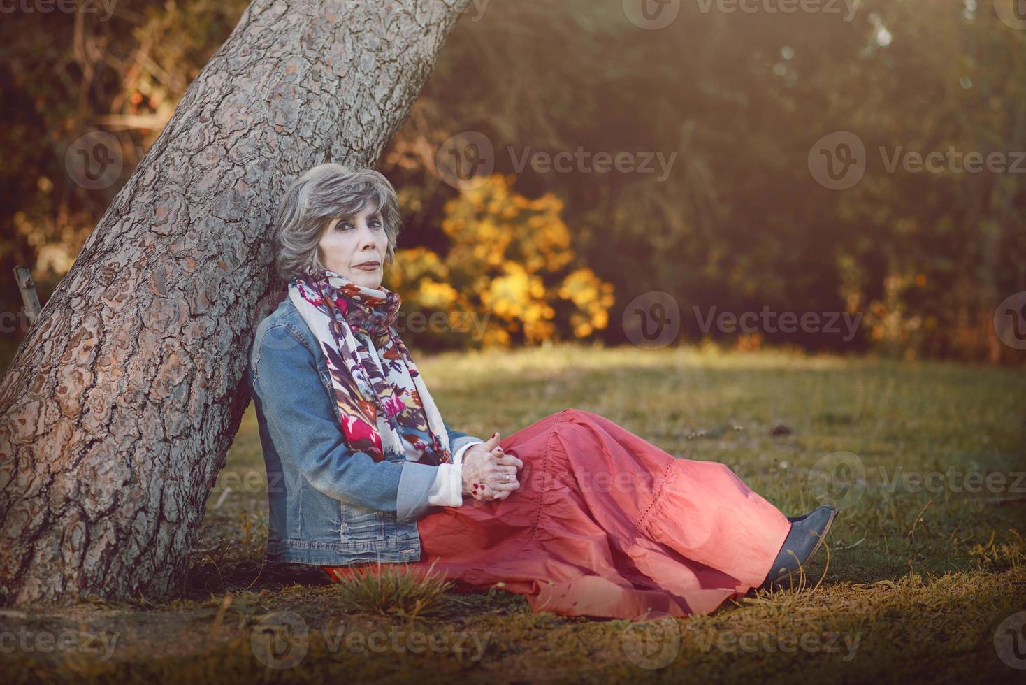 glückliche ältere Frau, die auf dem Gras sitzt foto