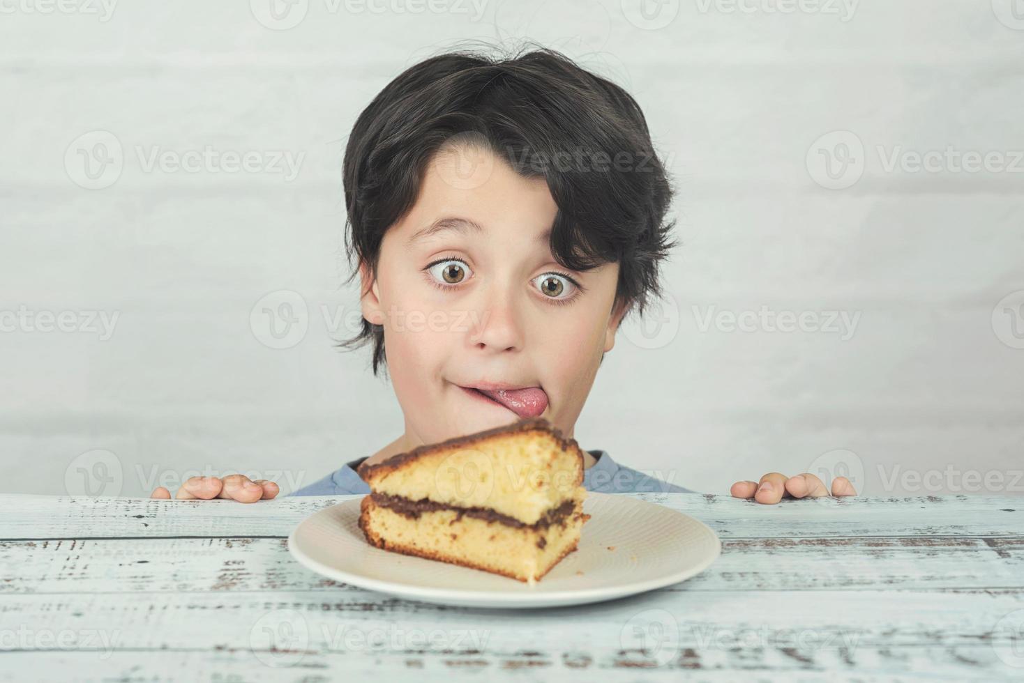 hungriges Kind, das Stück Kuchen isst foto