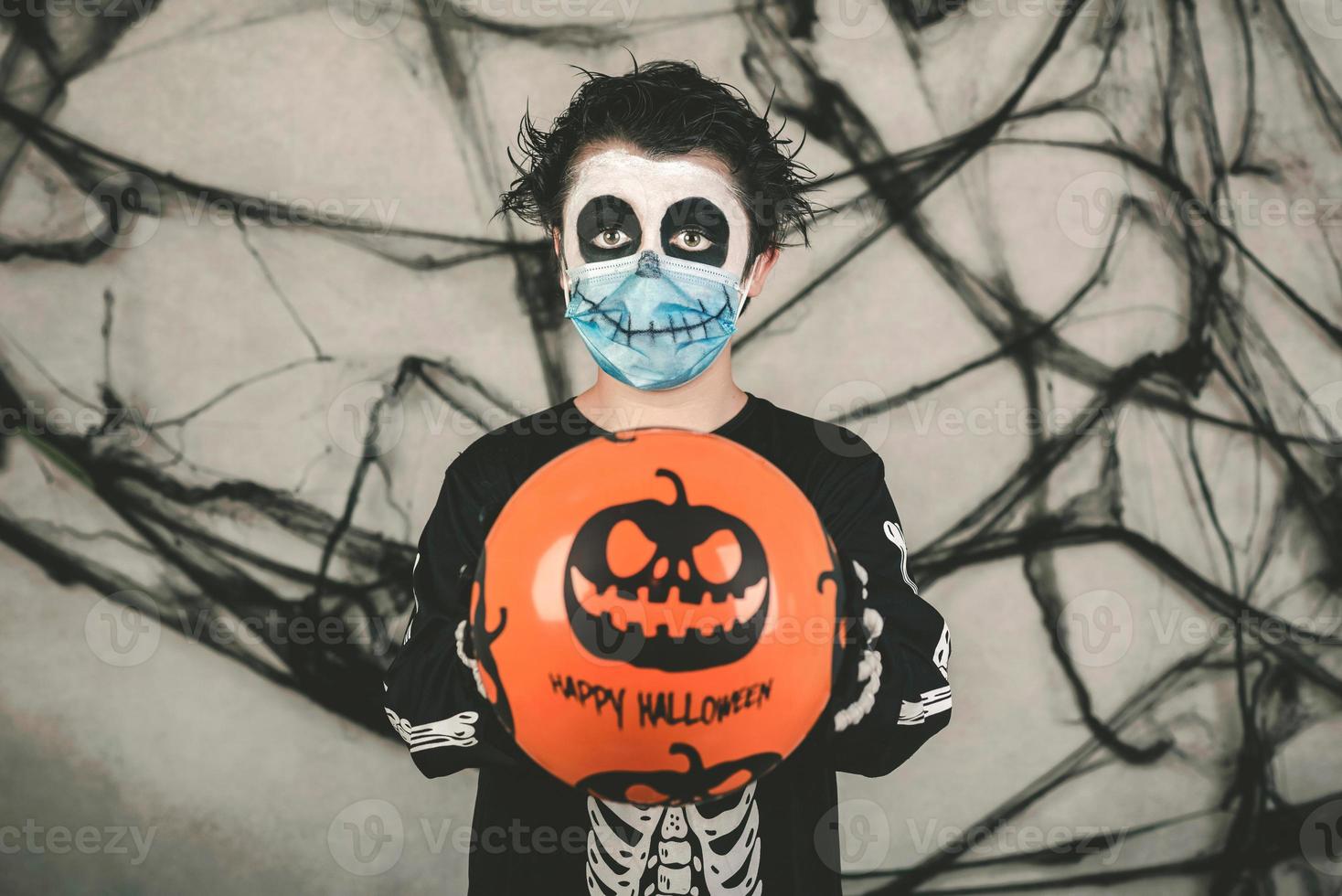 fröhliches halloween, kind mit medizinischer maske in einem skelettkostüm mit halloween-ballon foto