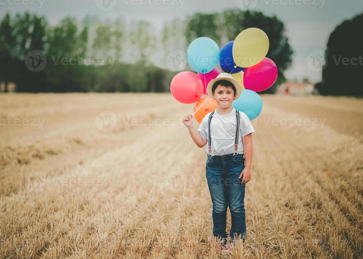 glückliches Kind mit Luftballons auf dem Feld foto