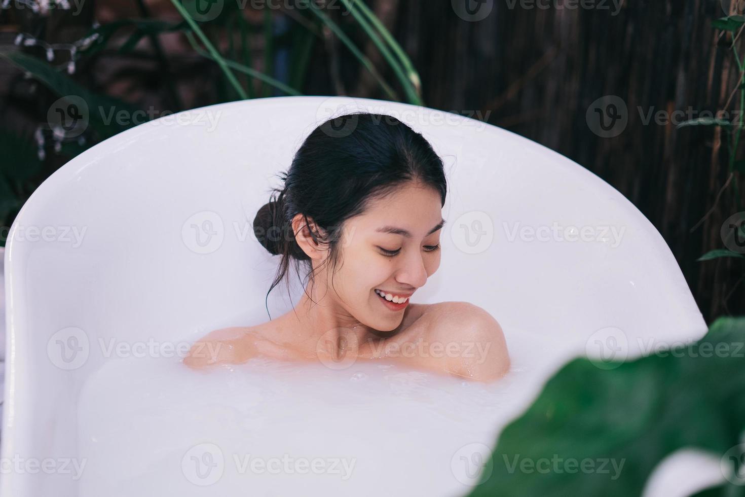 schöne junge asiatische frau, die im bad sich entspannt foto