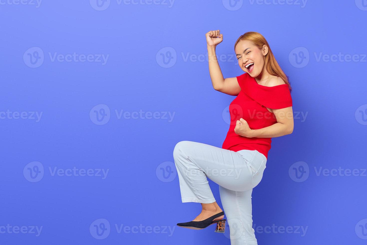 Porträt einer aufgeregten jungen Asiatin, die den Sieg einzeln auf violettem Hintergrund feiert foto