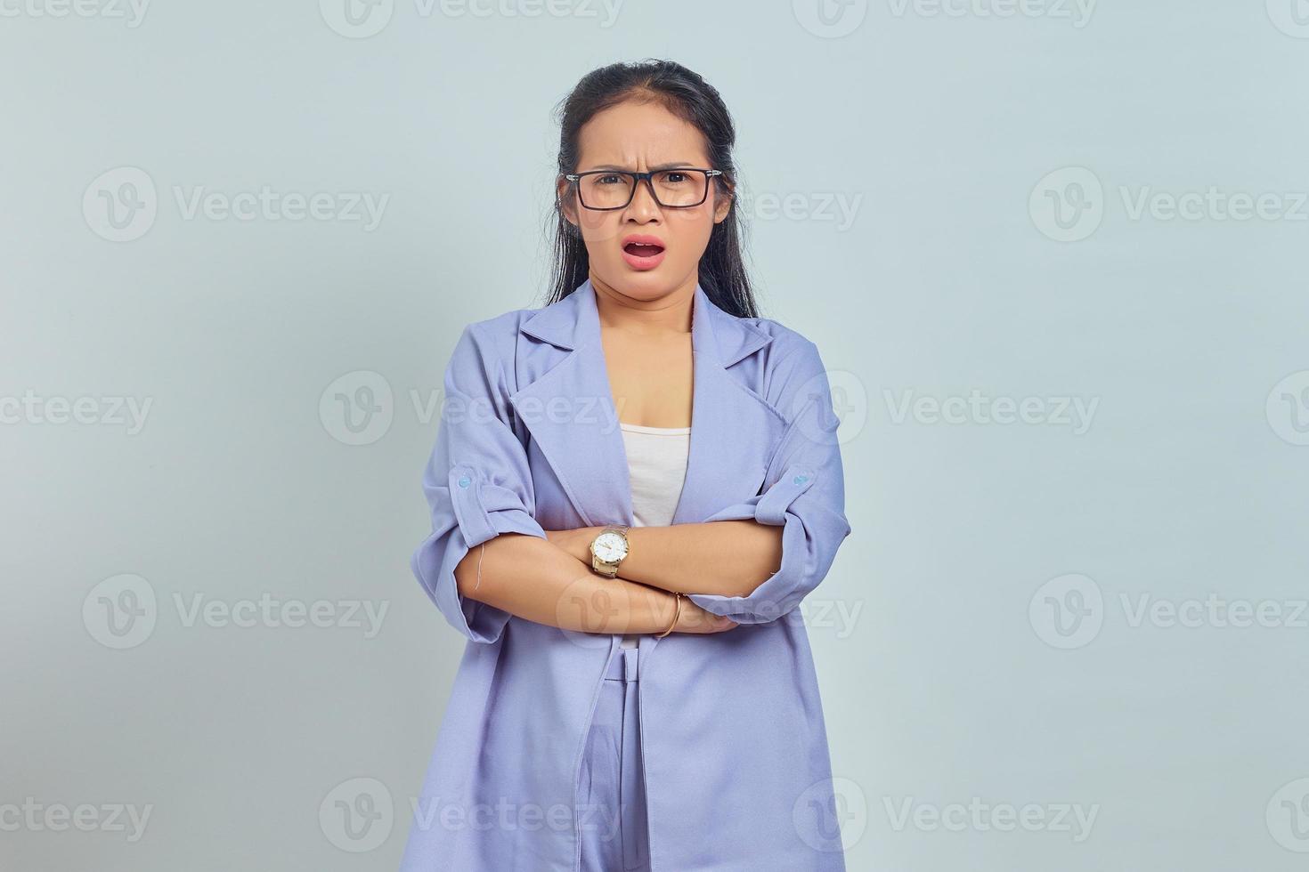 Porträt einer überraschten jungen asiatischen Frau, die mit verschränkten Armen steht und die Kamera isoliert auf weißem Hintergrund betrachtet foto