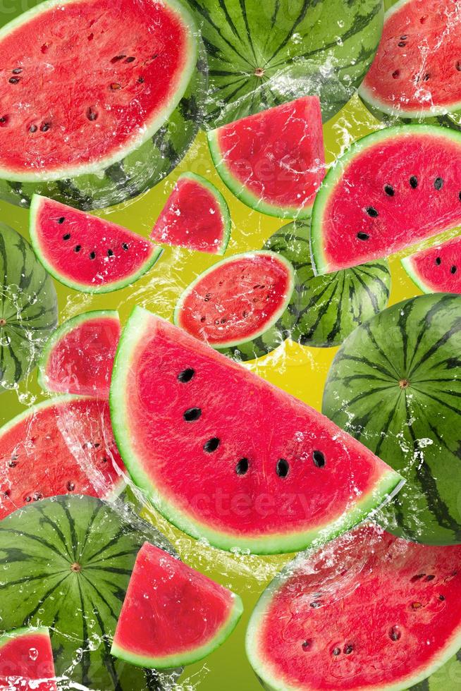 Wasser spritzt auf geschnittene Wassermelonenfrucht isoliert auf grünem Hintergrund foto