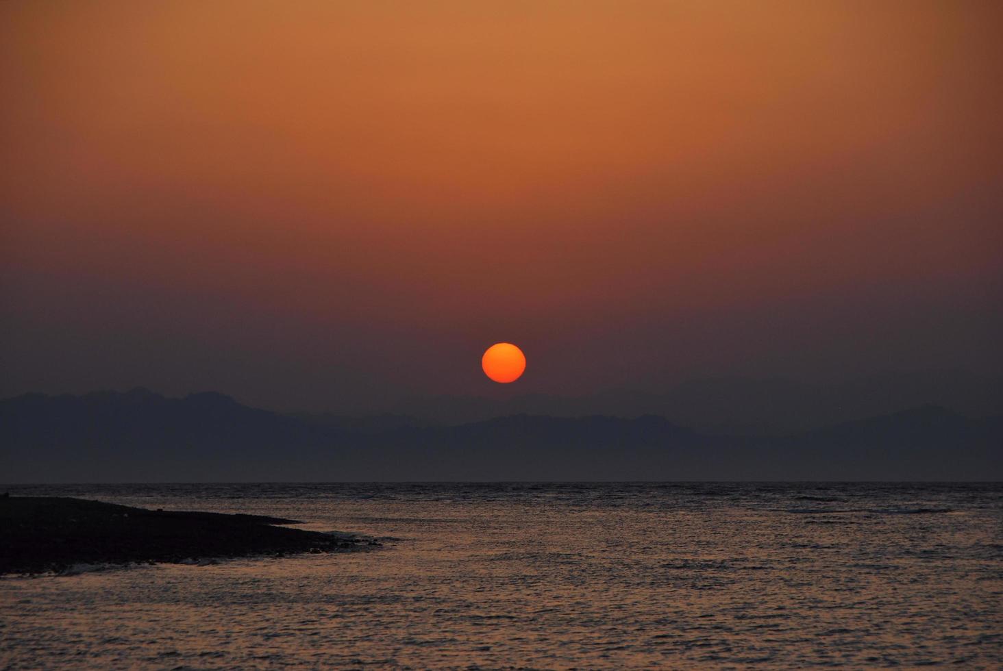 Rote Sonne bei Sonnenaufgang am Meer foto