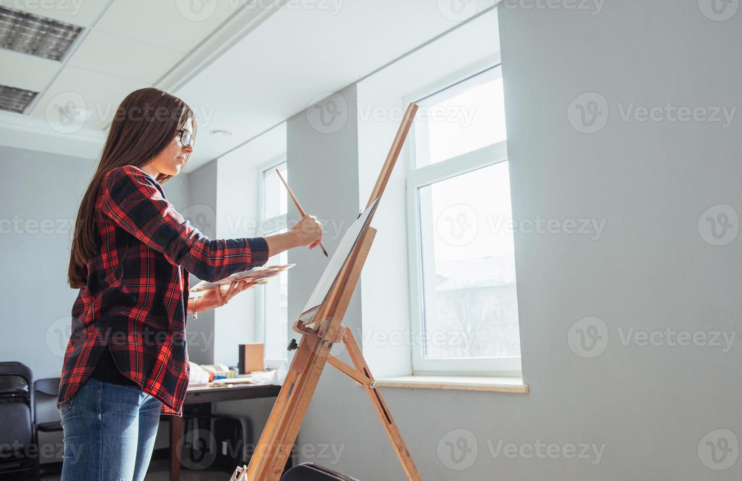 junge Künstlerin, die ein Bild im Studio malt foto