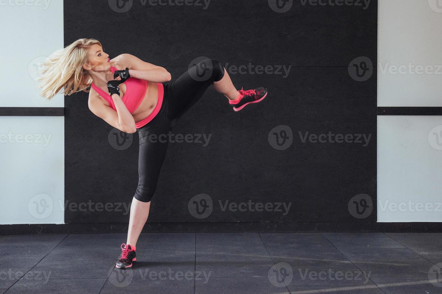 Boxerfrau, die im Fitnessstudio auf schwarz-weißem Hintergrund Kick gibt foto