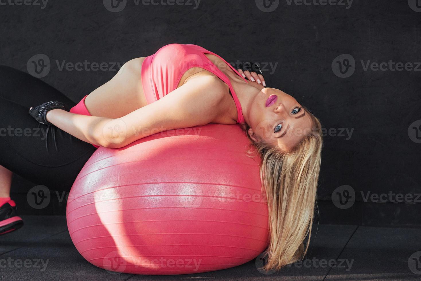 junge attraktive schlanke frau in sportbekleidung, die fitness-übungsball macht. foto