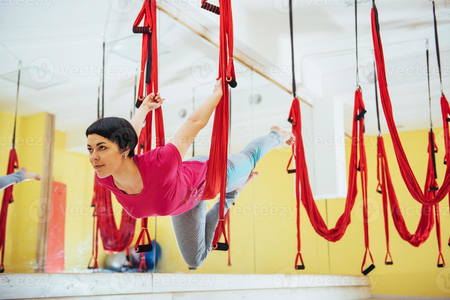 junge schöne frau, die yoga-fliege mit einer hängematte im hellen studio praktiziert. das Konzept der geistigen und körperlichen Gesundheit. foto