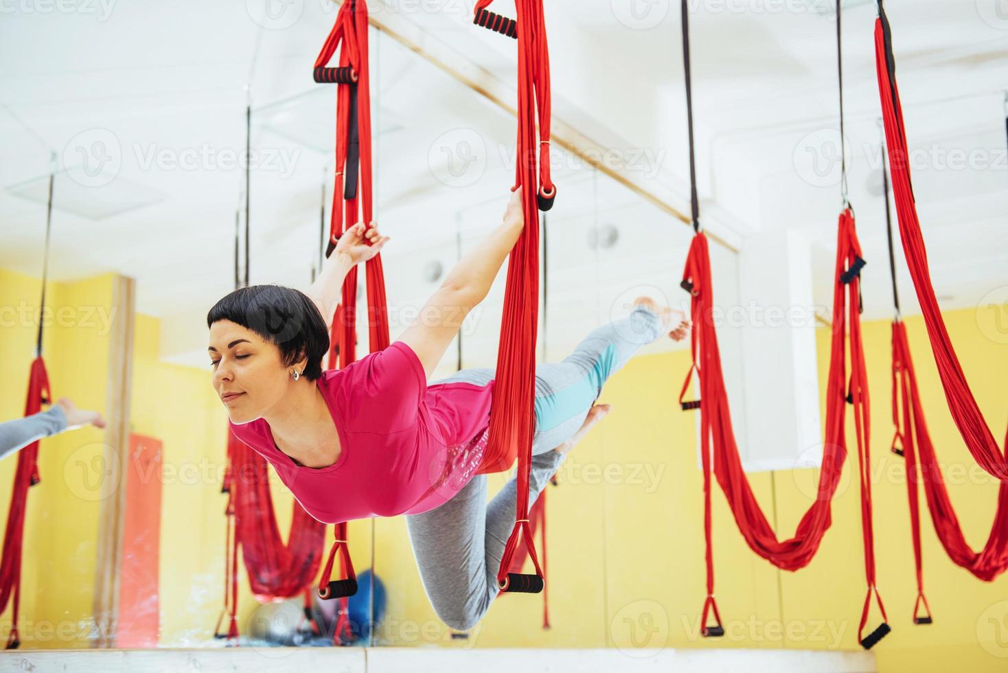 junge schöne frau, die yoga-fliege mit einer hängematte im hellen studio praktiziert. das Konzept der geistigen und körperlichen Gesundheit. foto