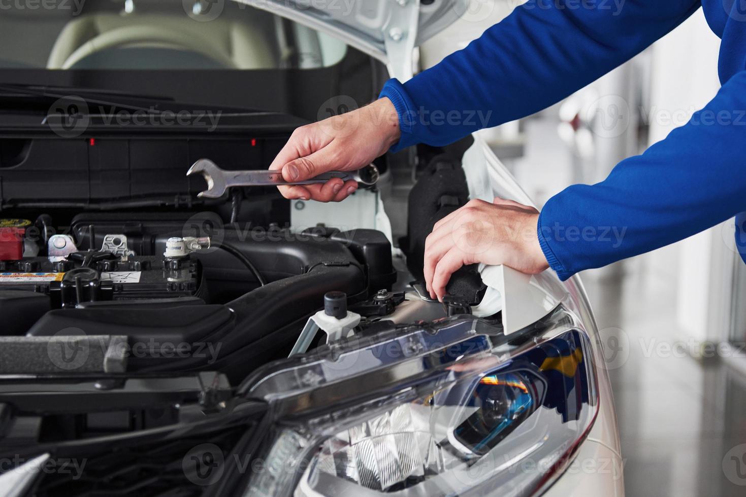 Hände des Automechanikers mit Schraubenschlüssel in der Garage foto