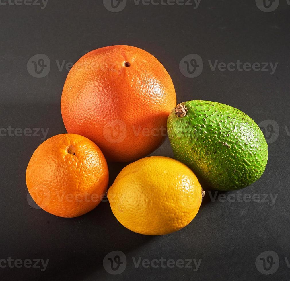 Köstliche frische Orange, Grapefruit, Avocado, Zitrone isoliert auf schwarzem Hintergrund. foto