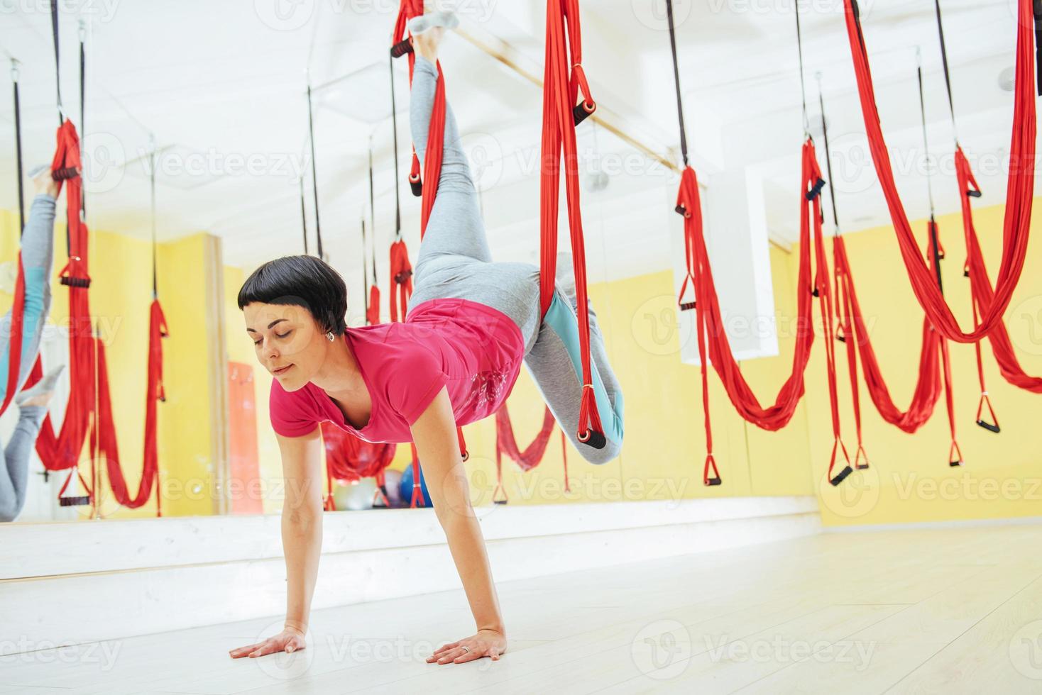 junge schöne frau, die yoga-fliege mit einer hängematte im studio praktiziert. foto