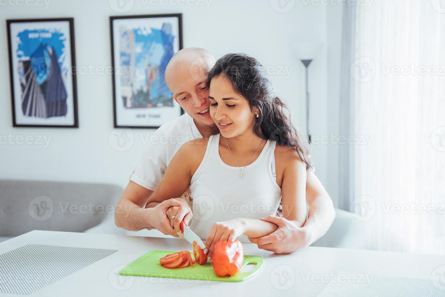 Schönes junges Paar mahlt Gemüse zusammen in der Küche. foto