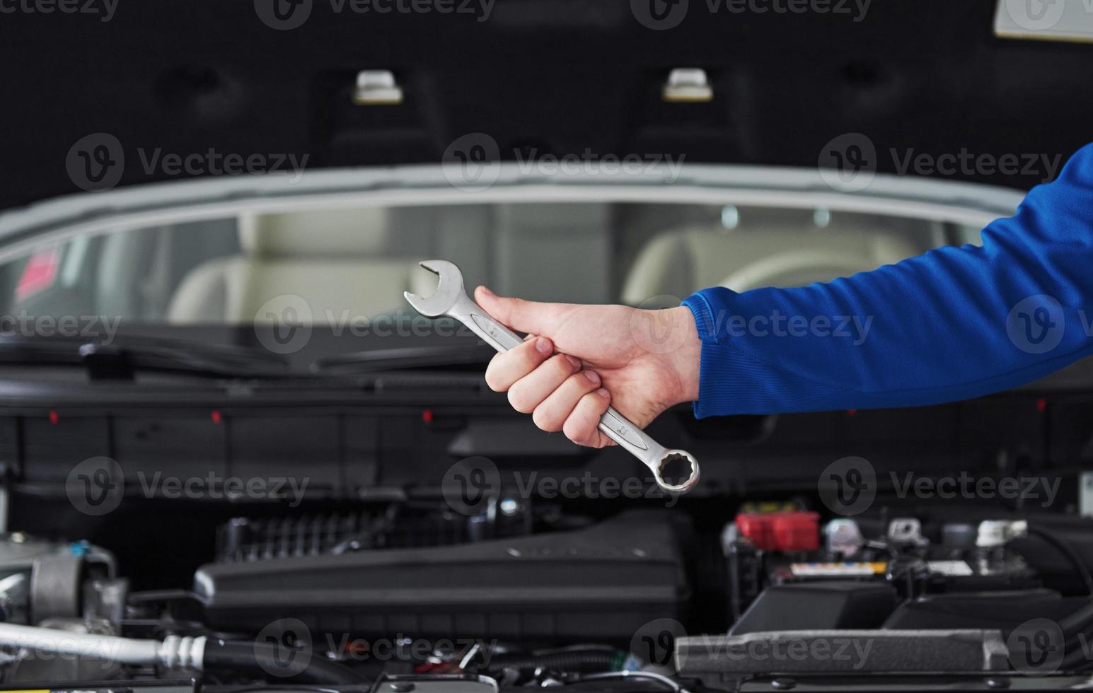 Hände des Automechanikers mit Schraubenschlüssel in der Garage foto