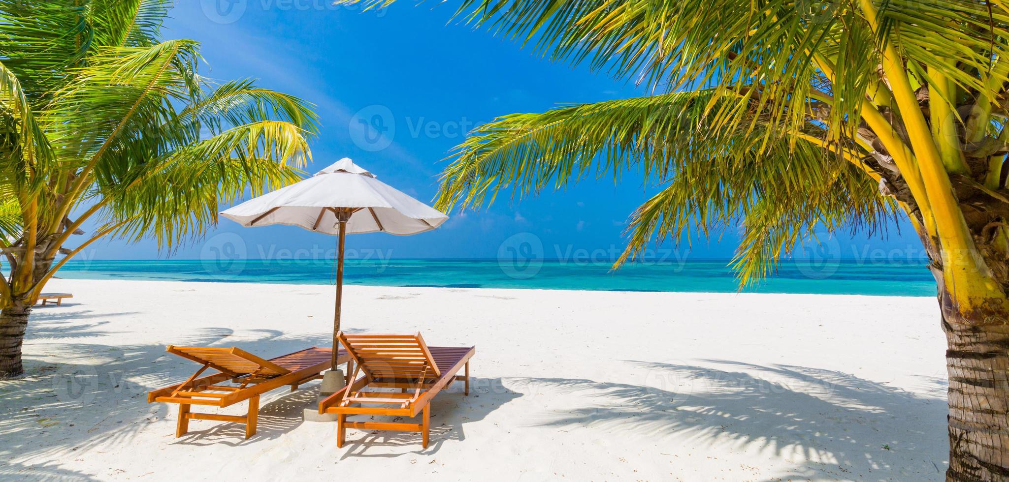 wunderschöne tropische Insellandschaft, zwei Sonnenliegen, Liegen, Sonnenschirm unter Palmen. weißer Sand, Meerblick mit Horizont, idyllischer blauer Himmel, Ruhe und Entspannung. inspirierendes Strandresorthotel foto