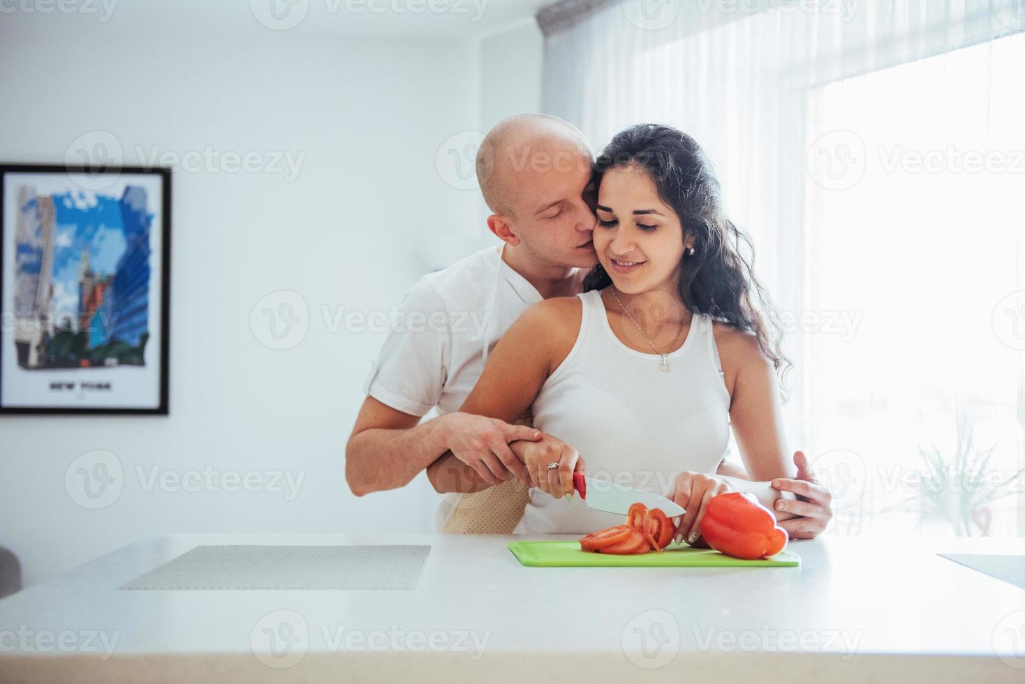 Schönes junges Paar mahlt Gemüse zusammen in der Küche. foto
