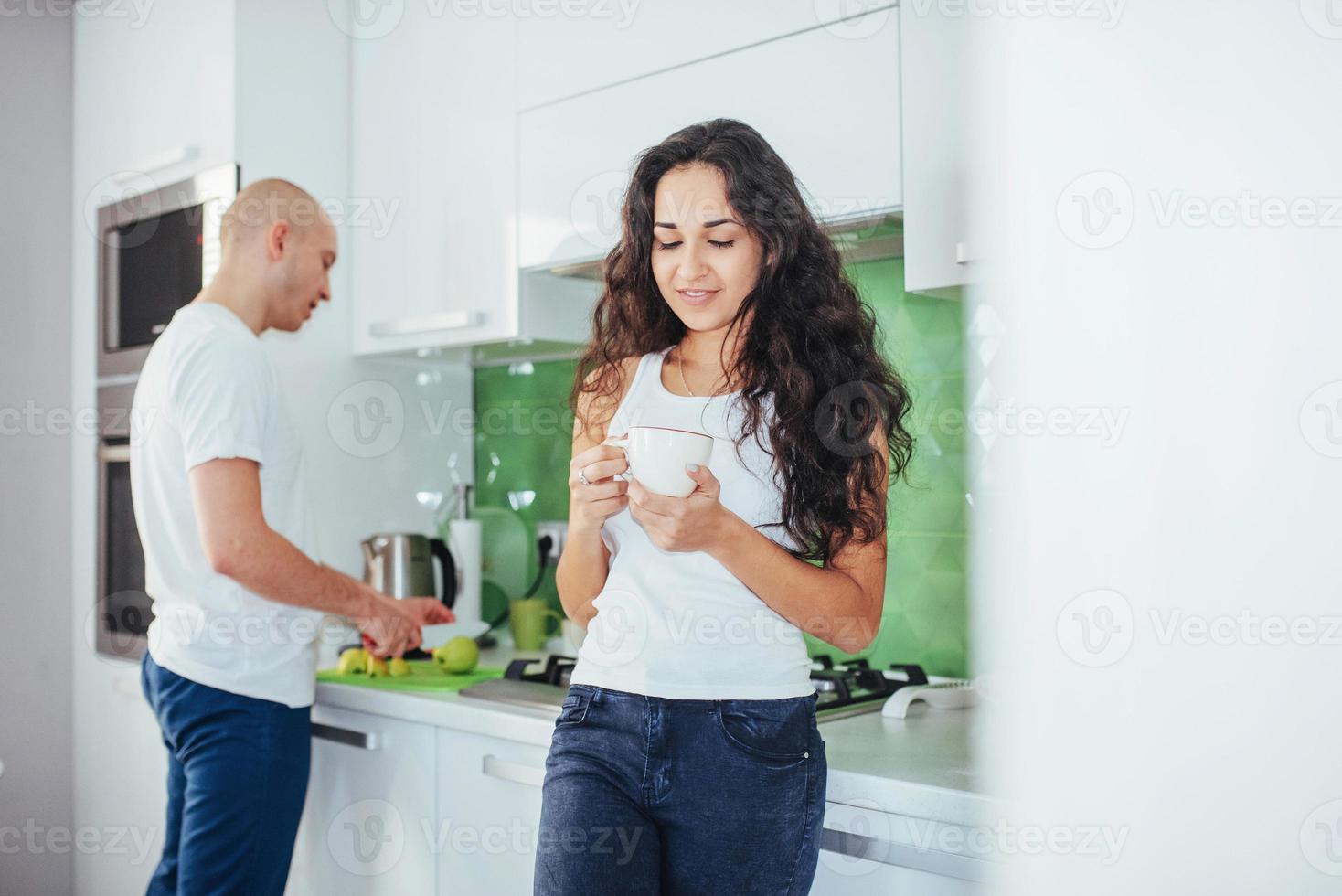 Schönes junges Paar spricht, schaut in die Kamera und lächelt beim Kochen in der Küche. foto