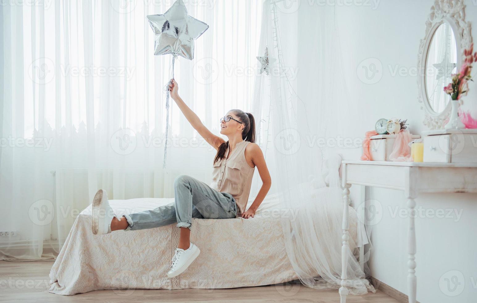 Nahaufnahme süßes brünettes Mädchen im Studio, breit lächelnd und mit transparenten und silbernen Luftballons spielend. foto