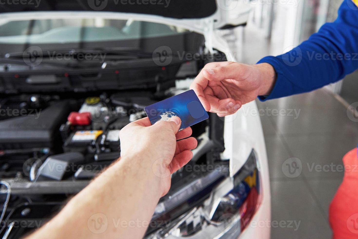 hände des automechanikers mit schraubenschlüssel in der garage, zahlung per kreditkarte foto