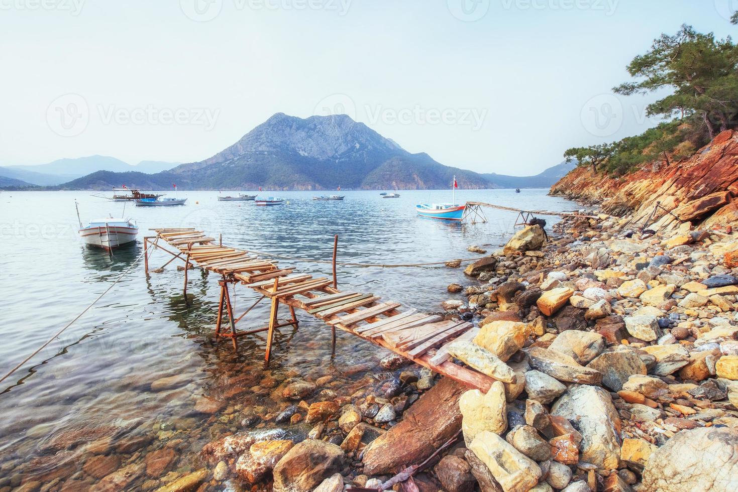 Boote in der Nähe des kaputten Piers, die in ein ruhiges, ruhiges blaues Meerwasser eintauchen foto