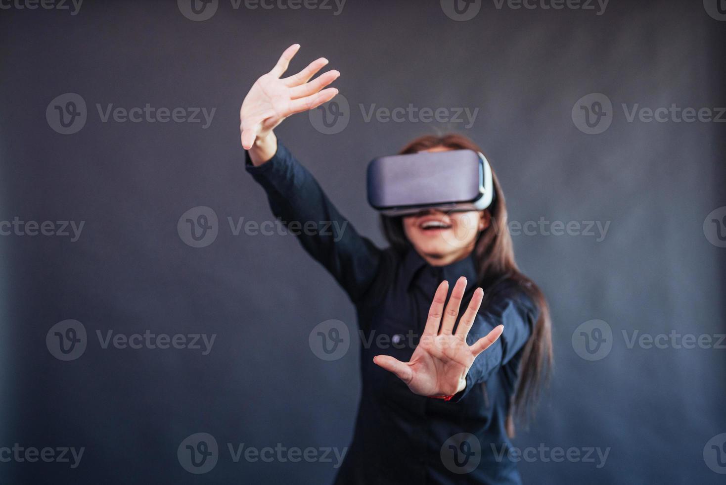 glückliche frau auf schwarzem hintergrund im studio bekommt die erfahrung mit dem virtual-reality-headset der vr-brille. foto