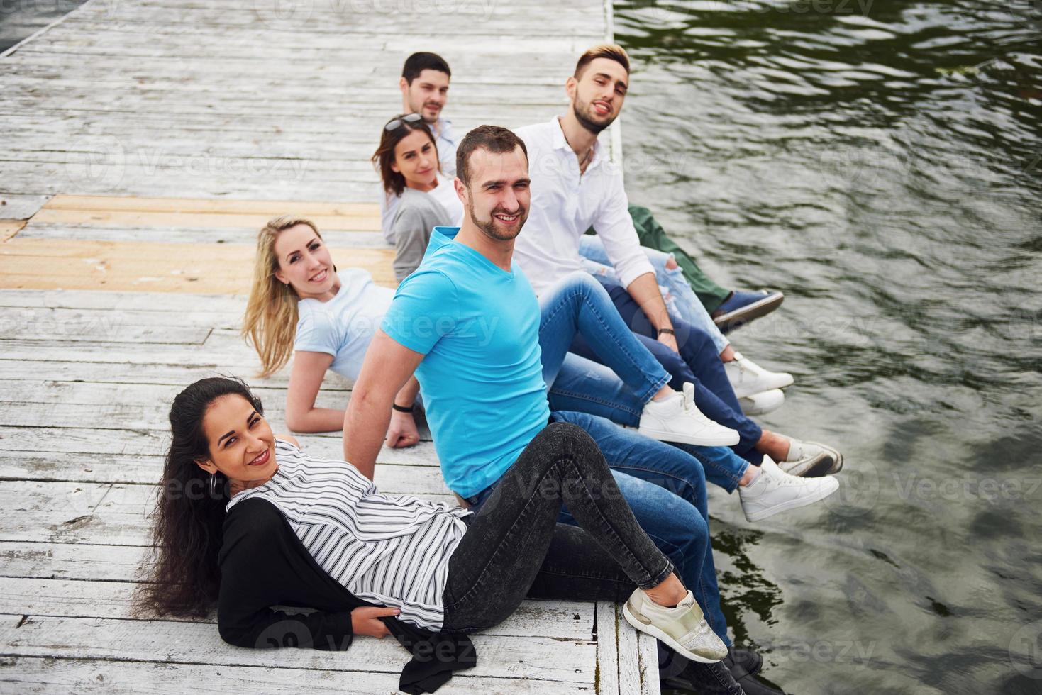 gruppe schöner junger leute auf dem pier, freundzufriedenheit schafft emotionales leben foto