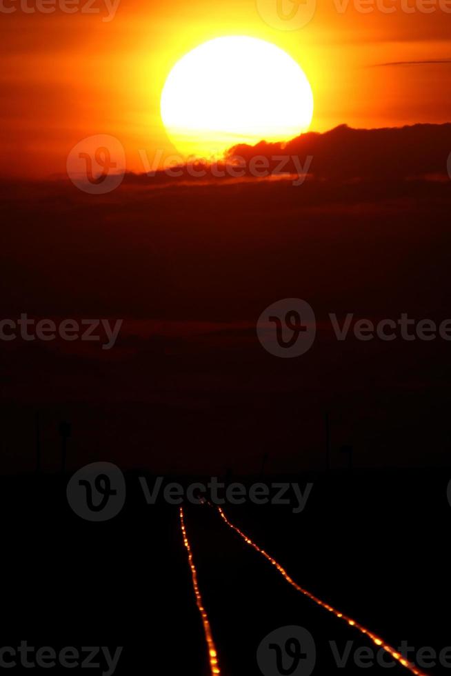 untergehende Sonne scheint auf Eisenbahnschienen foto