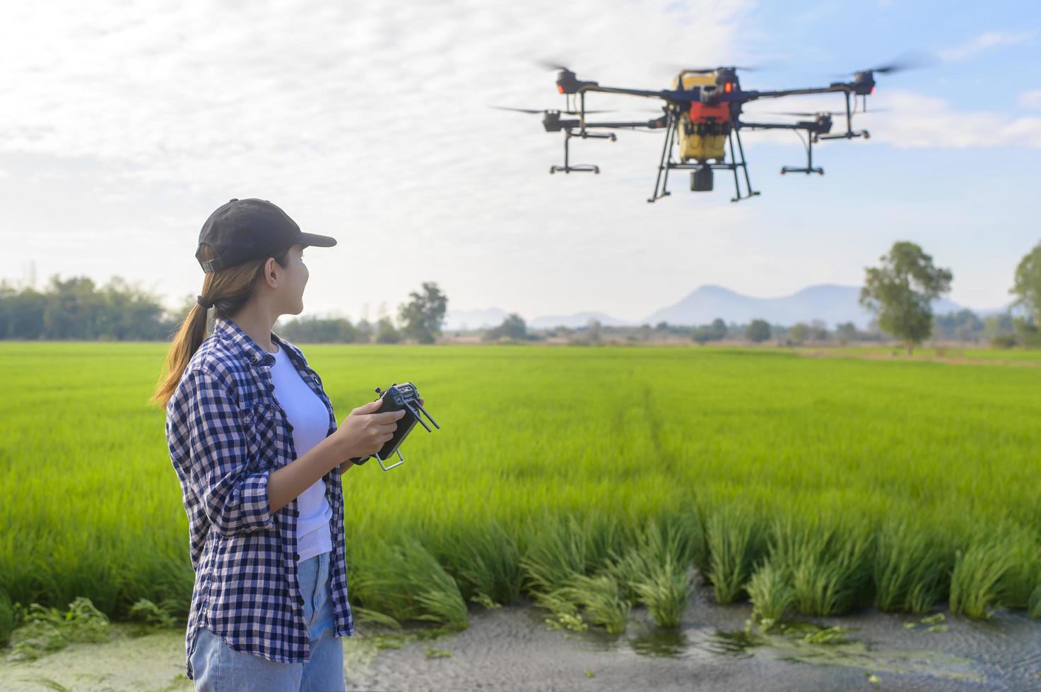 Junger intelligenter Landwirt, der Drohnen kontrolliert, die Düngemittel und Pestizide über Ackerland sprühen, hochtechnologische Innovationen und intelligente Landwirtschaft foto
