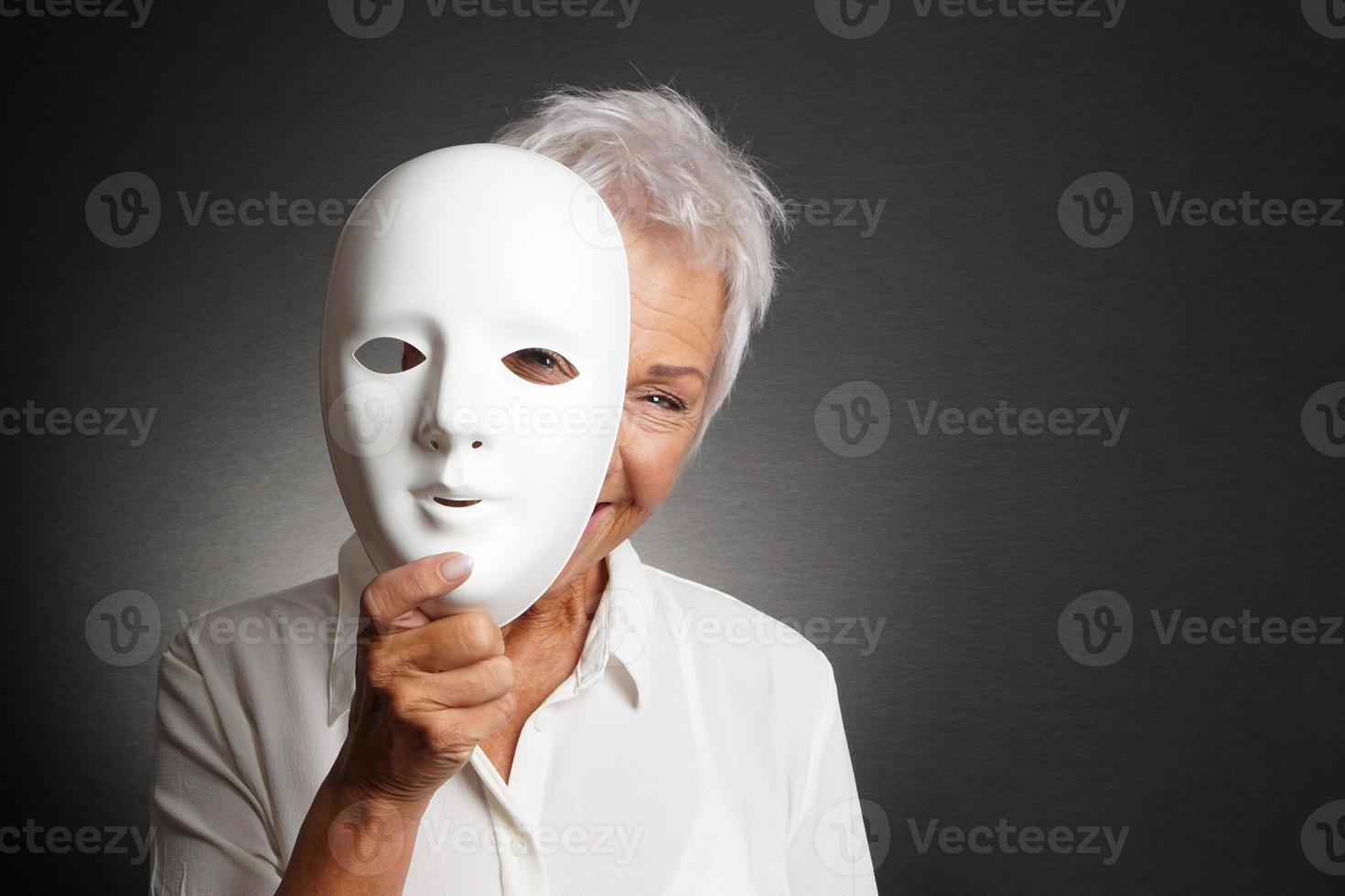 glückliche Seniorin, die hinter der Maske hervorschaut foto