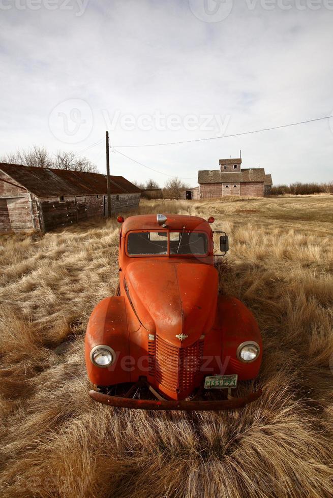 Alter landwirtschaftlicher Lastwagen, der in der Nähe von ungenutzten Holzgebäuden aufgegeben wurde foto