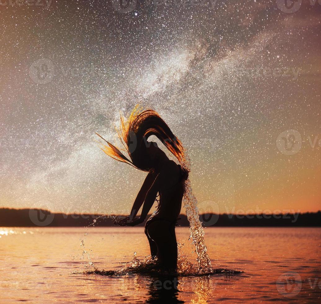 Frau auf Wasserhintergrund am Nachthimmel. fantastischer Sternenhimmel und die Milchstraße foto