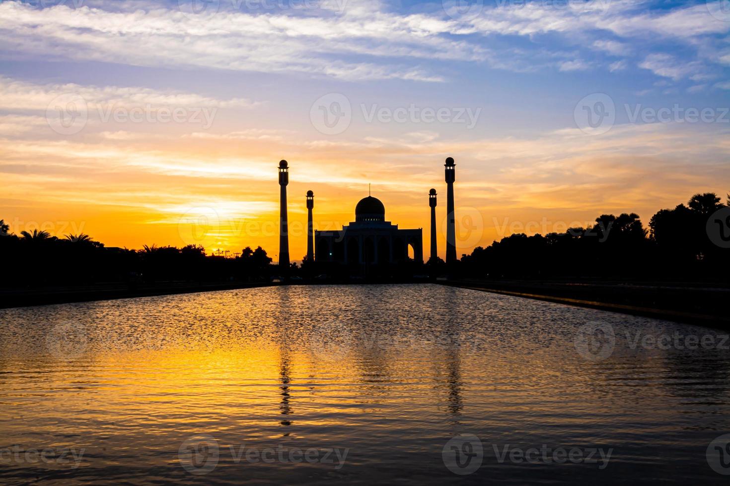 songkhla zentrale moschee von tag zu nacht mit farbenfrohen himmeln bei sonnenuntergang und den lichtern der moschee und reflexionen im wasser in einem wegweisenden landschaftskonzept foto