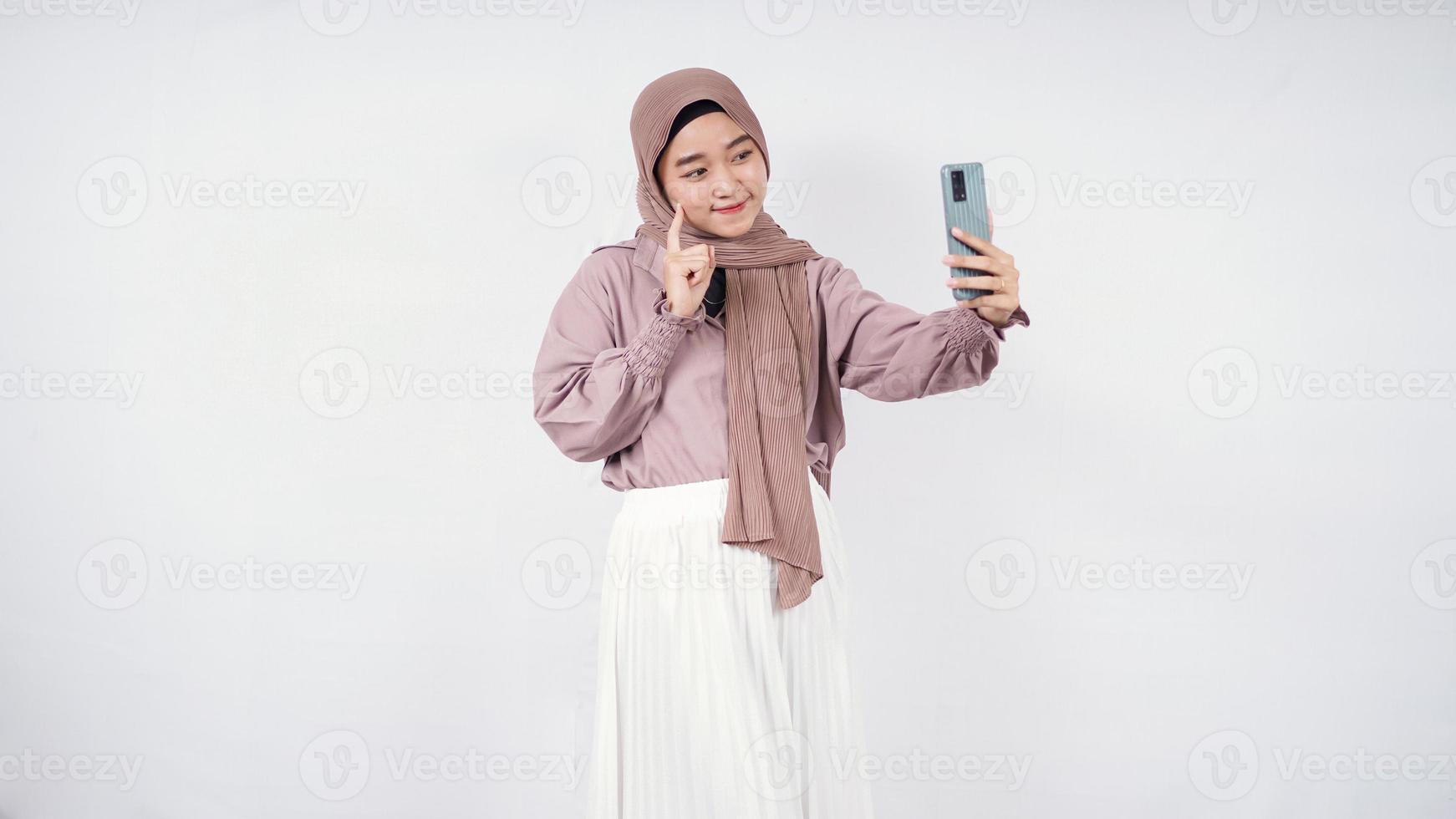 schöne Frau im Hijab lächelnden Ausdruck zeigt auf süße Wange isoliert auf weißem Hintergrund foto