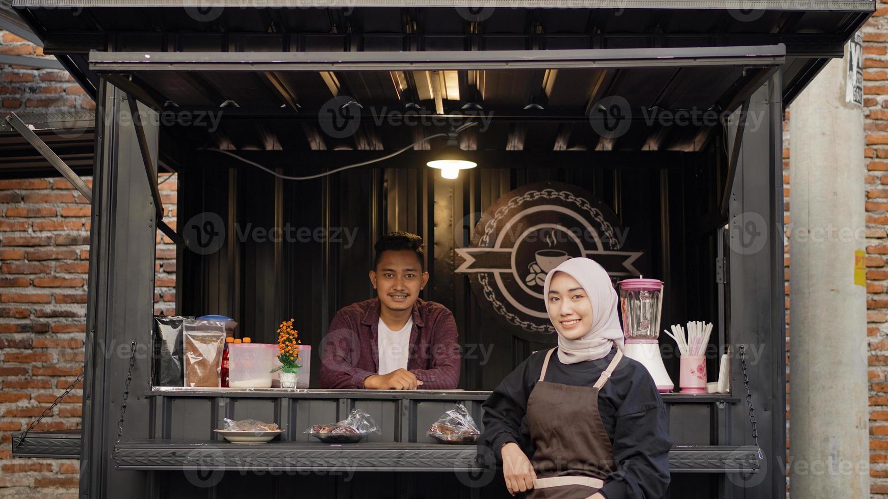 schöne asiatische kellnerin und cooler gutaussehender kerl am angkringan containerstand foto