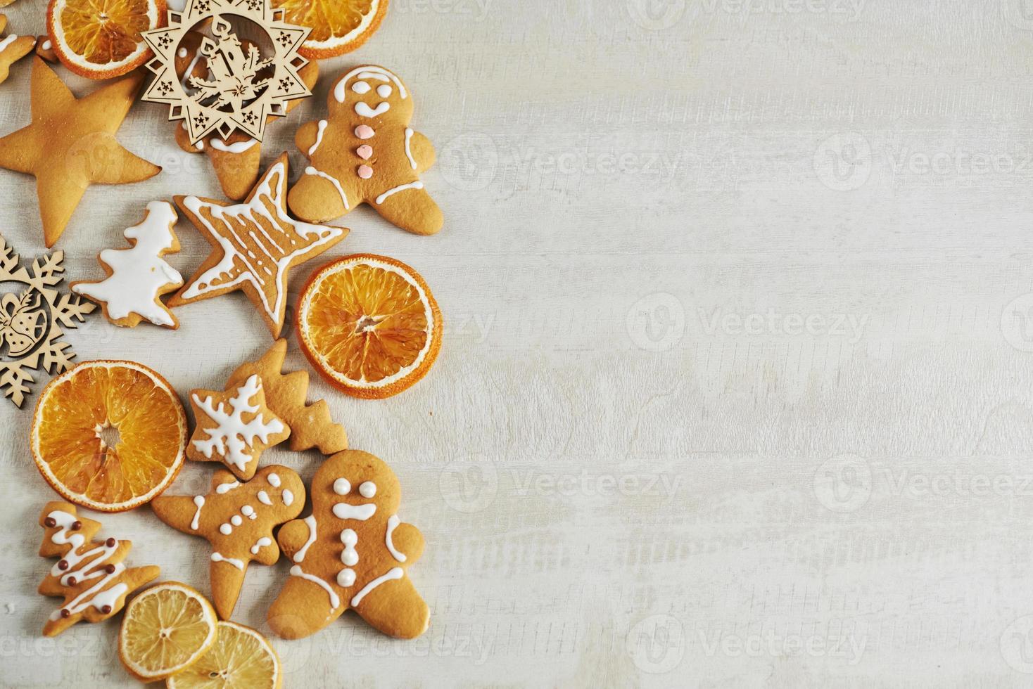 weihnachtslebkuchenplätzchen und getrocknete orange und gewürze auf weißem tisch foto