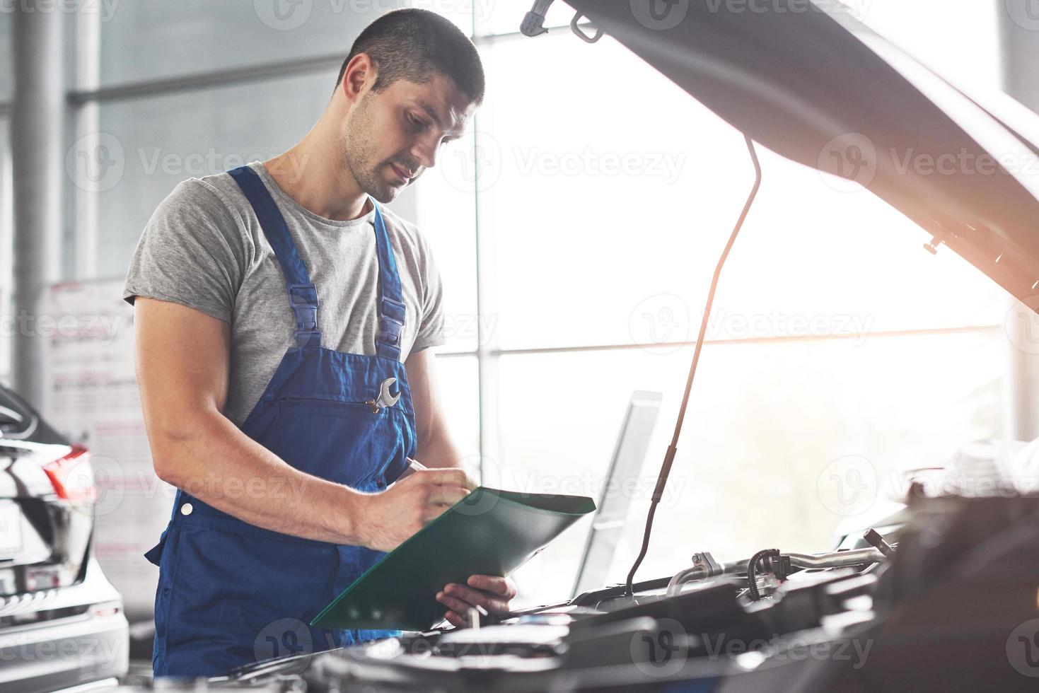 Bild, das einen muskulösen Autoservice-Mitarbeiter zeigt, der das Fahrzeug repariert foto