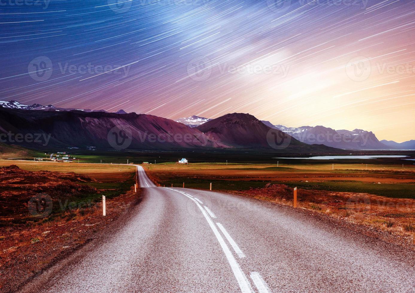 Sternenhimmel über den Bergen. die Asphaltstraße mit weißen Markierungen. schöne Sommerlandschaft. weicher Filtereffekt. Island foto