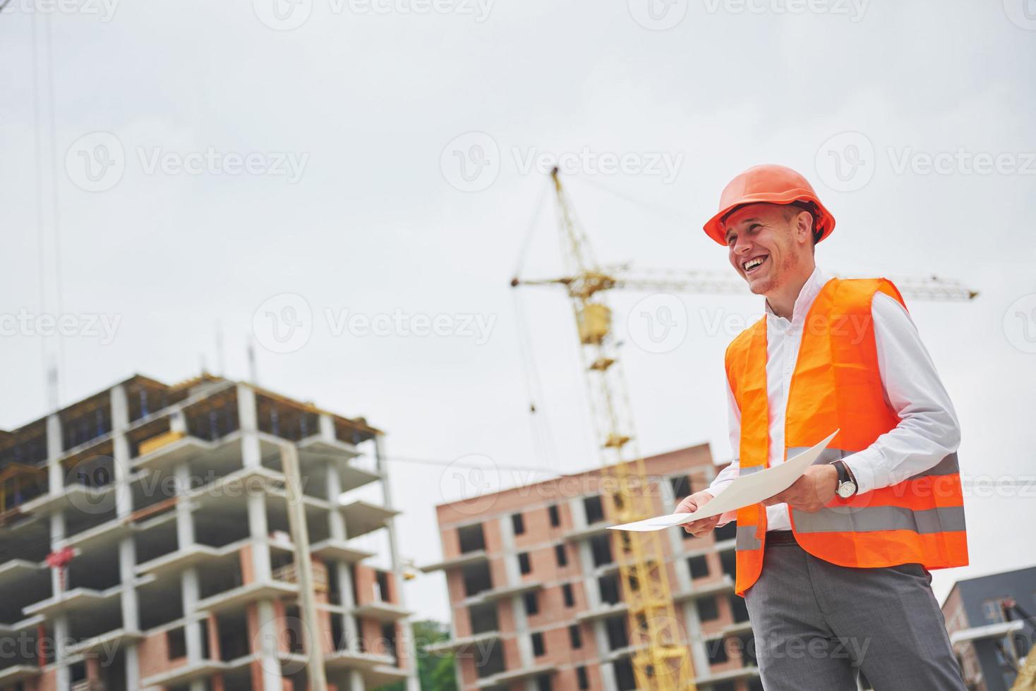 architektur- und hausrenovierungskonzept - mann in helm und handschuhen mit bauplan in der fabrik foto