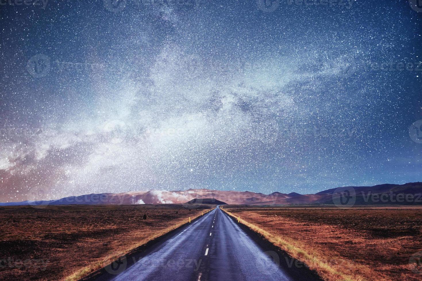 Sternenhimmel über den Bergen. die Asphaltstraße mit weißen Markierungen. schöne Sommerlandschaft. weicher Filtereffekt. Island foto