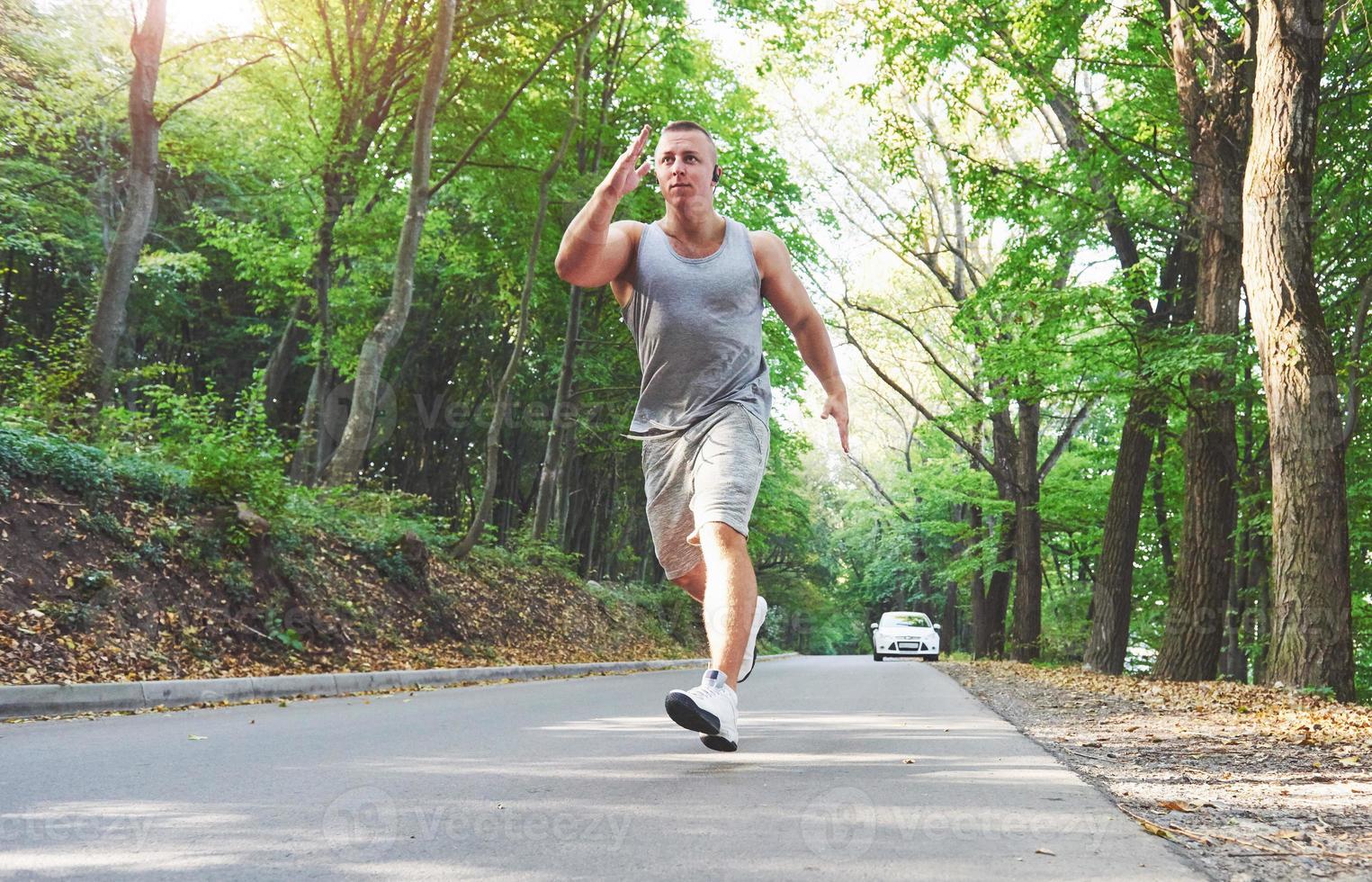 Fitness-Mann-Athlet, der bei Sonnenuntergang in der Natur joggt. Person, die im Sommer in Sportbekleidung und Schuhen einen aktiven Lebensstil trainiert und Cardio trainiert. foto