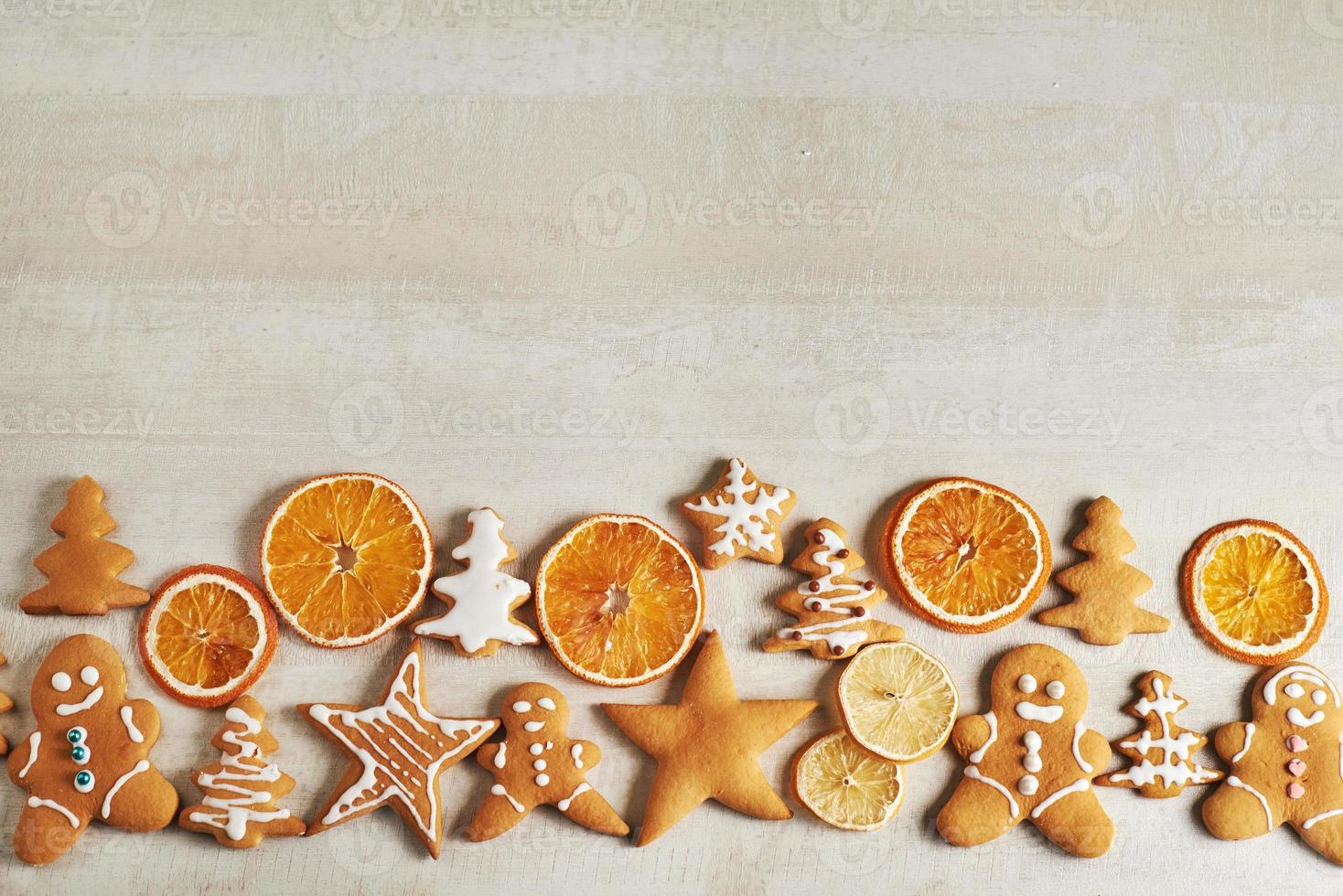 weihnachtslebkuchenplätzchen und getrocknete orange und gewürze auf weißem tisch foto