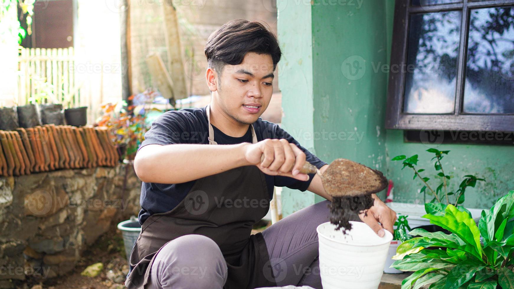 asiatischer mann bereitet einen platz zum pflanzen mit topf und erde vor foto