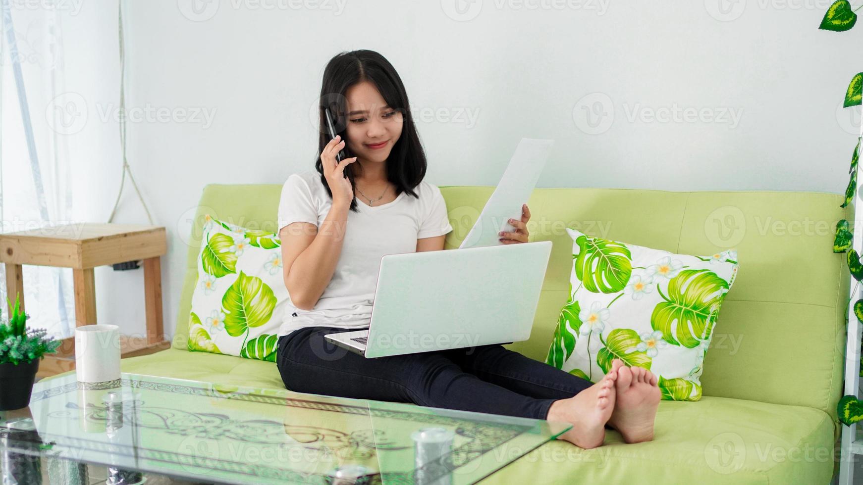 schöne asiatische frauen, die von zu hause aus mit laptop arbeiten und telefonieren foto