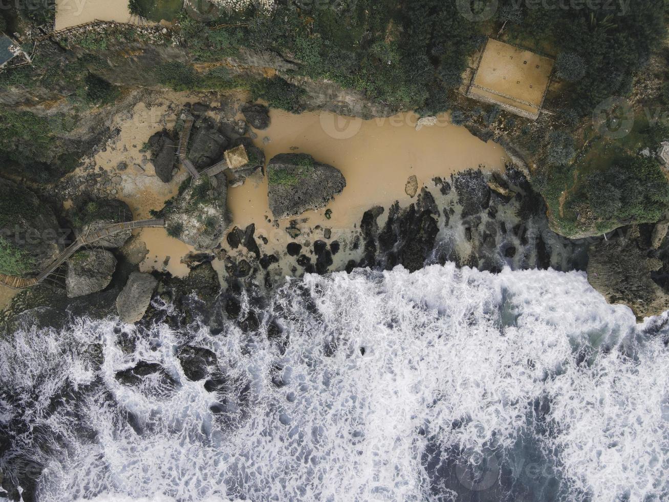 Luftaufnahme von oben nach unten von riesigen Meereswellen, die am Korallenstrand zusammenbrechen und schäumen foto