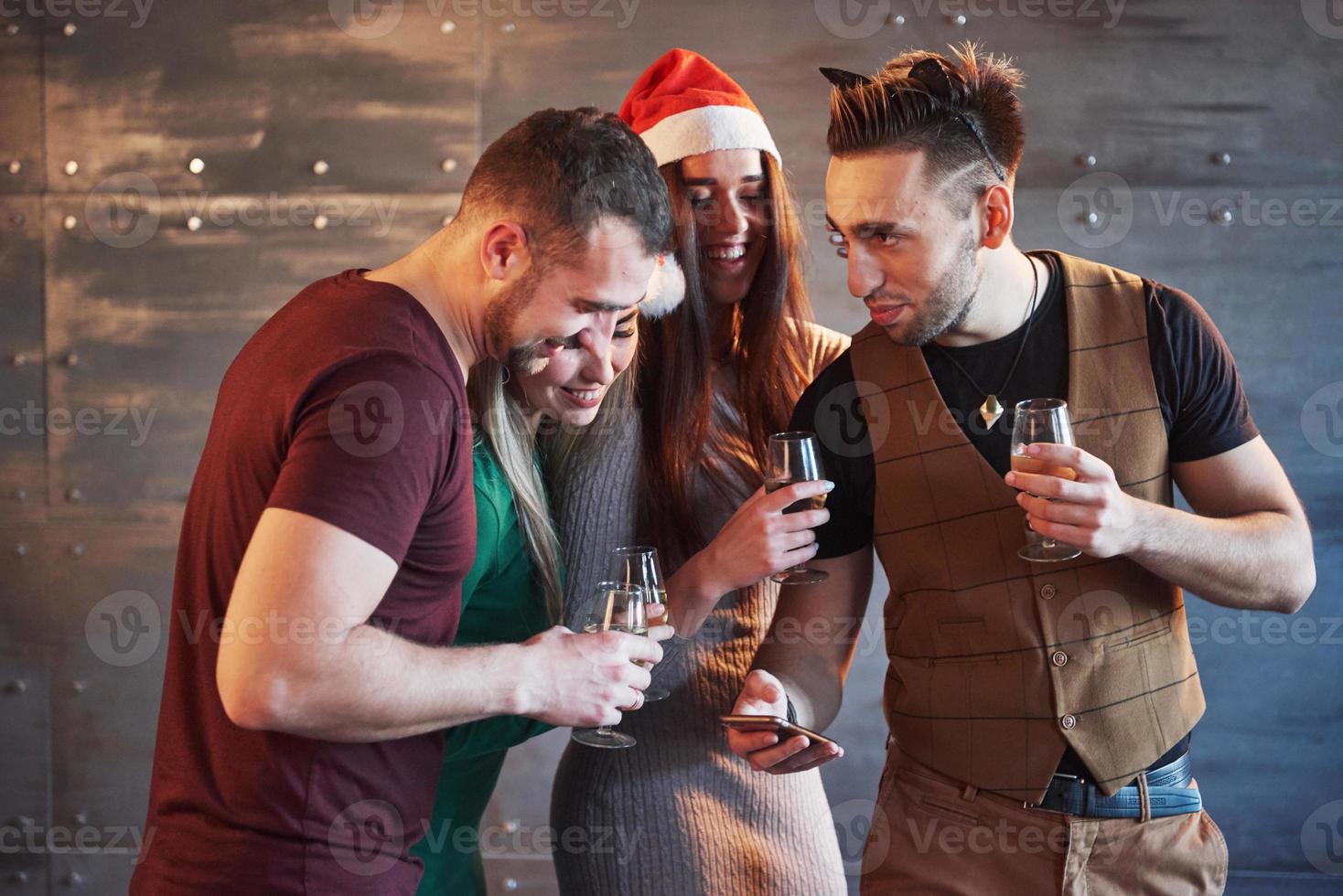 fröhliche alte freunde kommunizieren miteinander und telefonieren, mit gläsern champagner in der neujahrsparty. Konzept der Unterhaltung und des Lebensstils. WLAN-verbundene Menschen foto