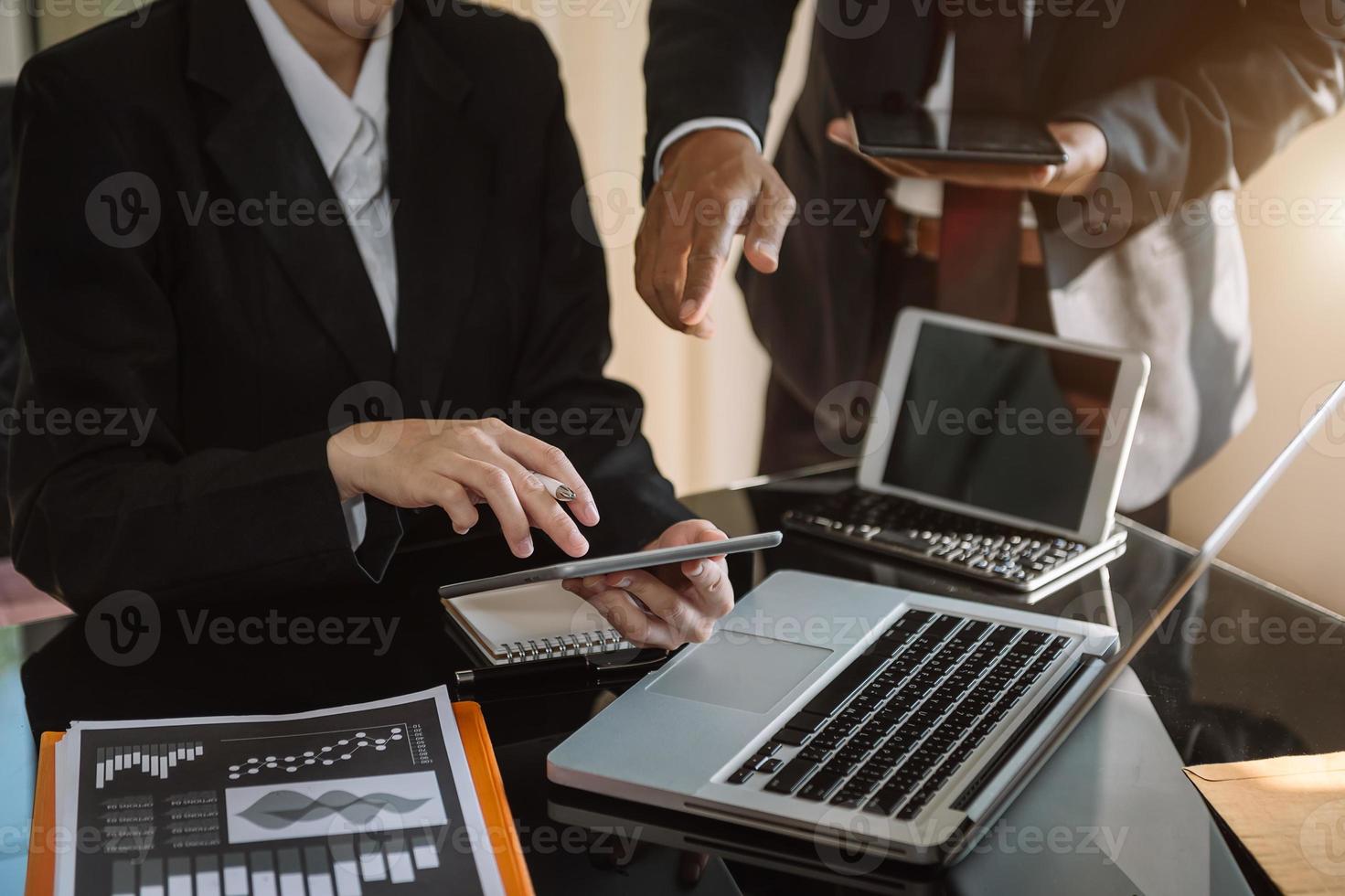 Geschäftsmannhand mit Laptop und Tablet mit sozialem Netzwerkdiagramm und zwei Kollegen, die Daten auf dem Schreibtisch als Konzept im Morgenlicht diskutieren. foto