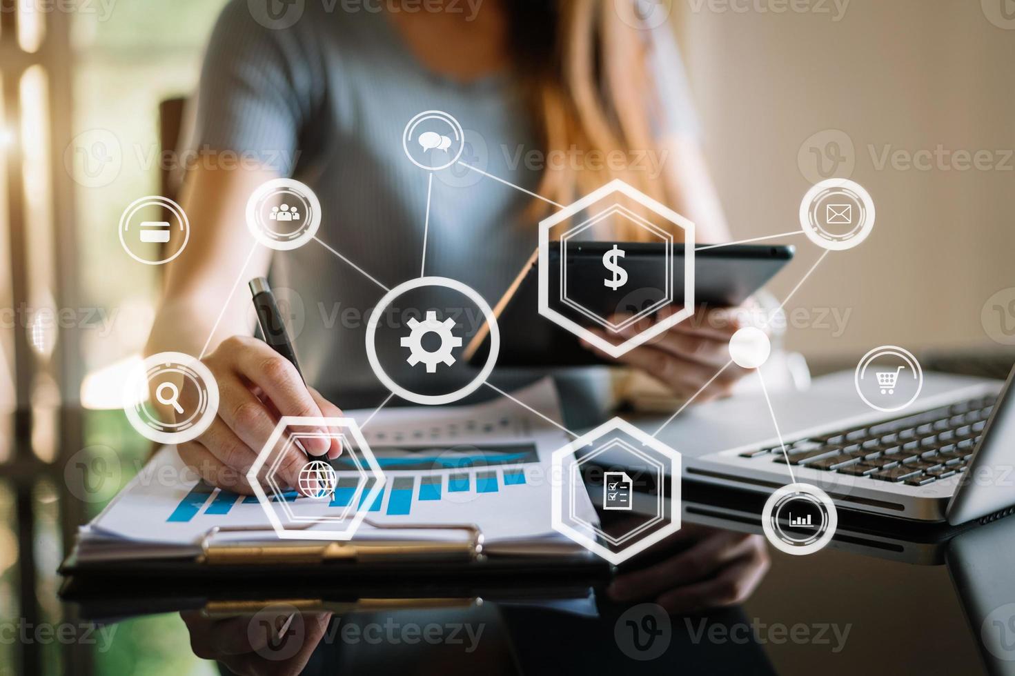 Geschäftsfrau arbeitet mit Laptop-Computer und Tablet im modernen Büro mit virtuellem Symboldiagramm foto